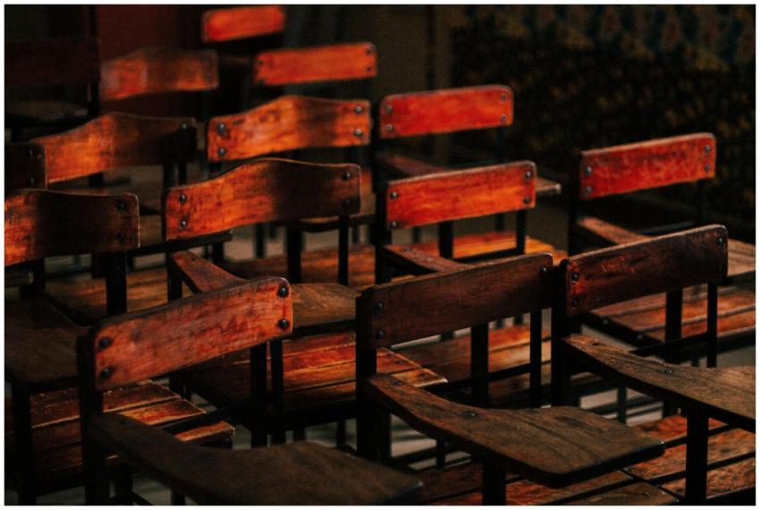A collection of vintage wooden classroom chairs in