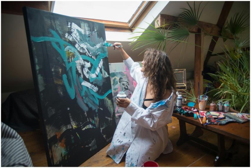 Artist painting on a large canvas in a cozy, well-