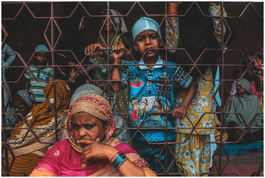 A diverse group of people gathered behind a fence,