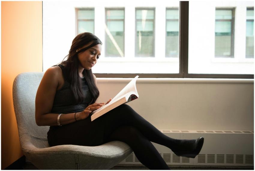 A thoughtful woman reading a book while sitting by