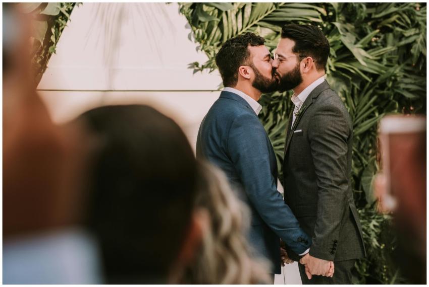 A same-sex couple shares a tender kiss at their we