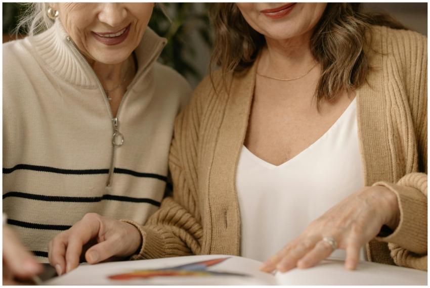 Two senior women enjoy reading a book together ind