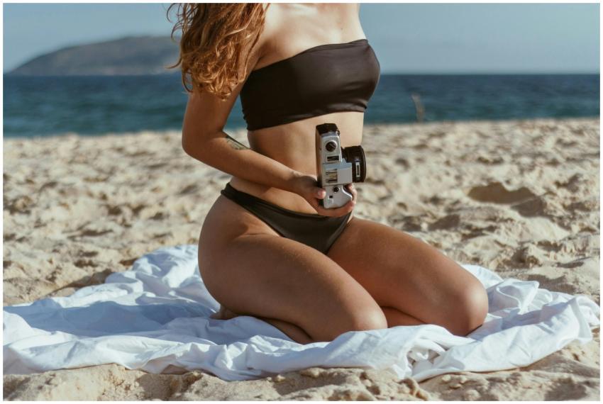 Young woman in a bikini holding a vintage camera o