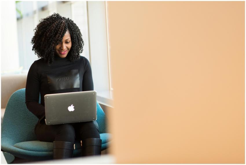 African American woman happily working on a laptop