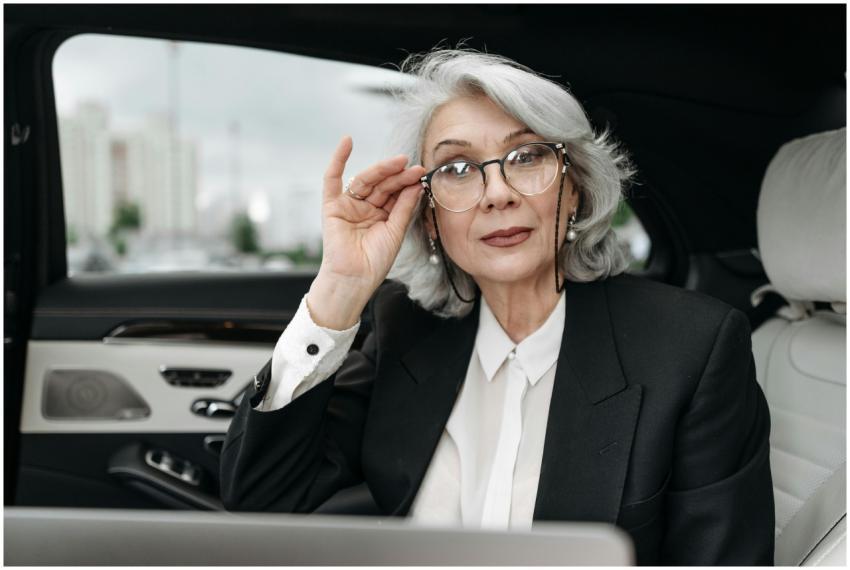 Stylish senior woman in a suit adjusting her glass