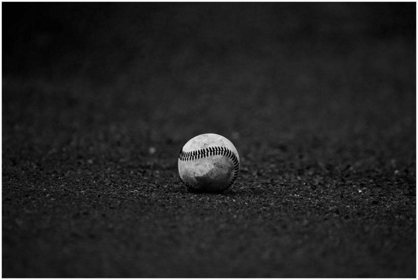A monochrome image of a baseball resting on a text