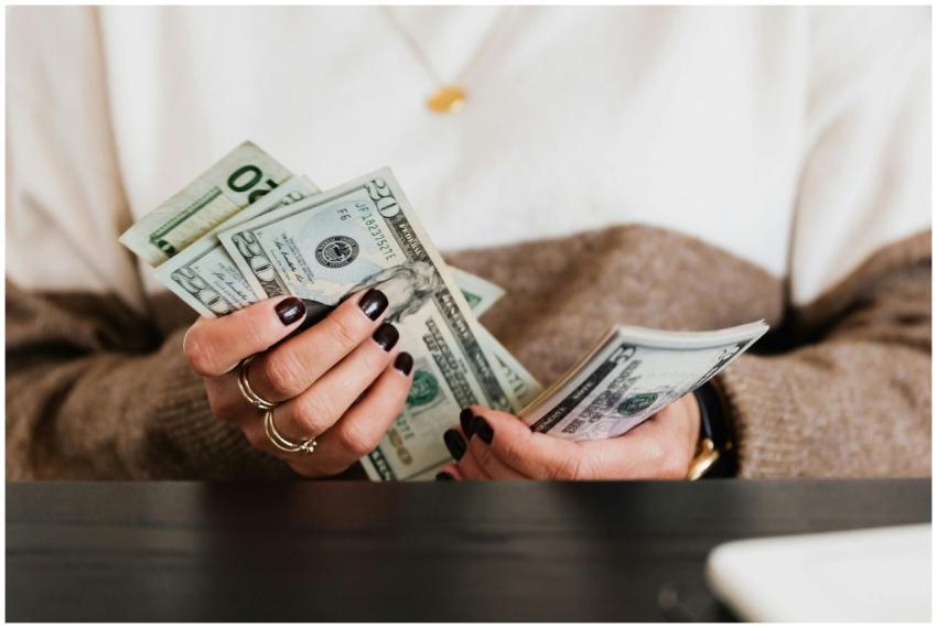 Close-up of hands counting US dollar bills, depict