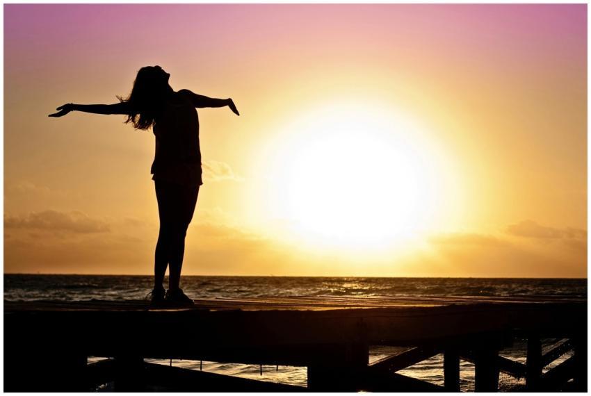 A joyful silhouette of a woman standing on a dock
