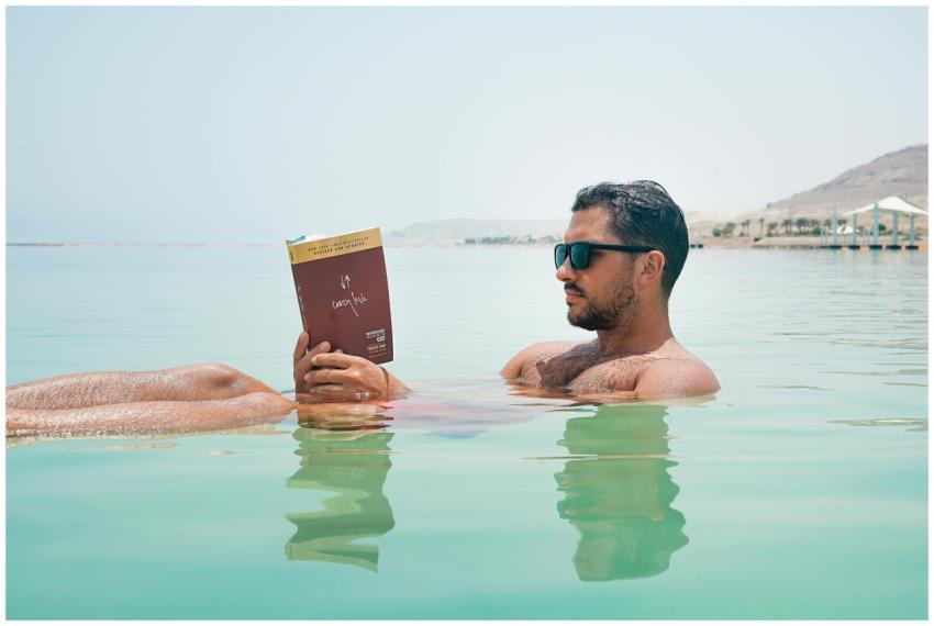 Relaxing man reading a book while floating on the