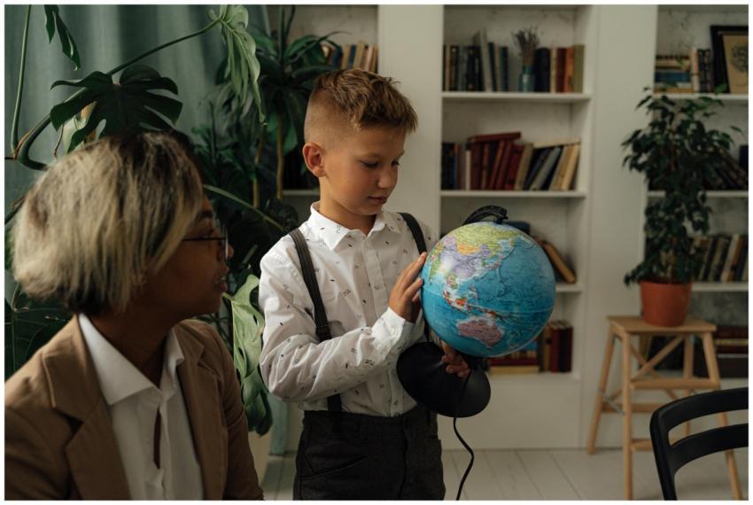 A young boy studying geography indoors with a glob