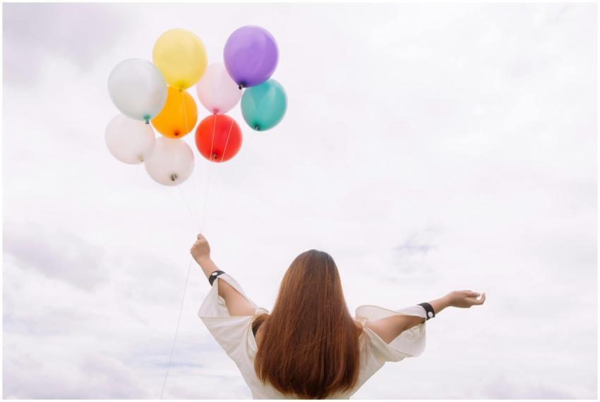 Young woman with arms wide open holds colorful bal