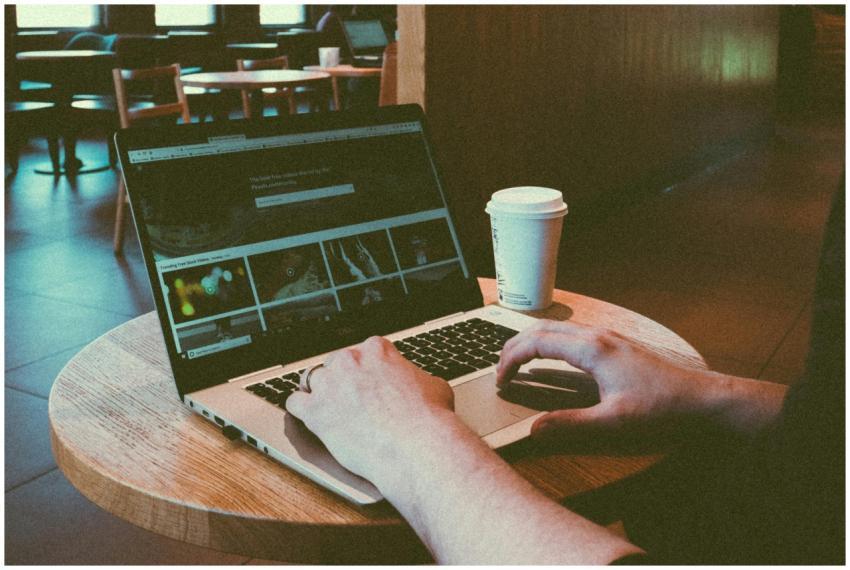Person using a laptop in a cozy café, highlighting
