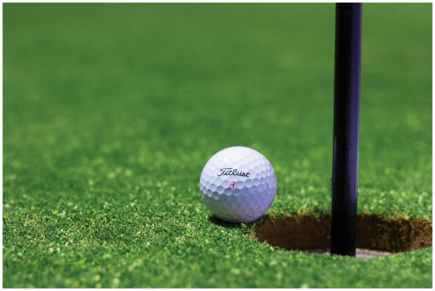 Close-up of a golf ball near a hole on a vibrant g