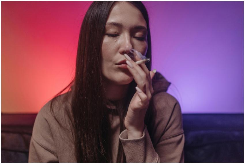 Woman in casual hoodie smoking cannabis in ambient