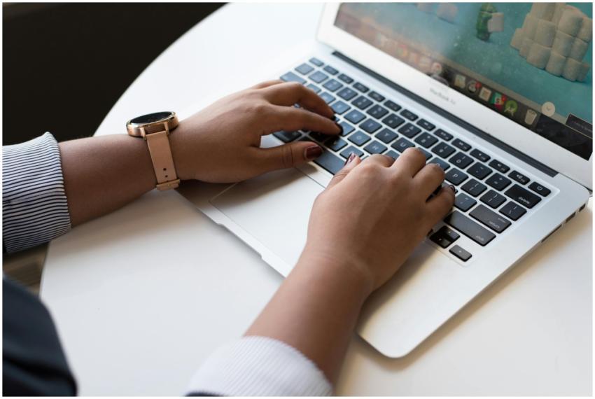 Close-up of a woman typing on a laptop in a modern