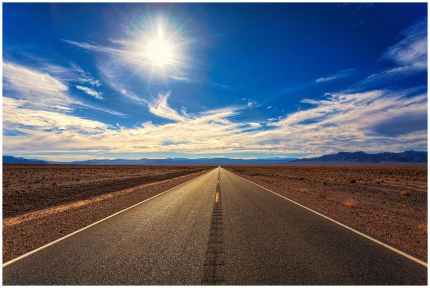 A long, straight road stretches across a dry deser