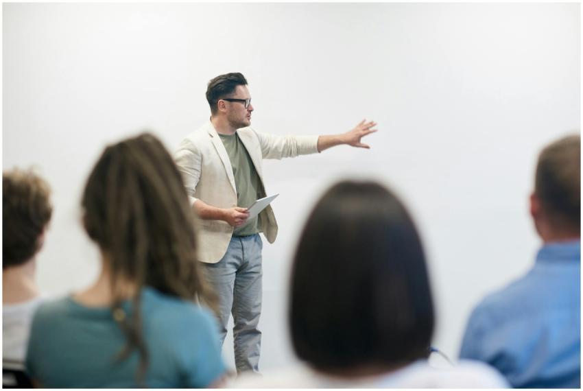 A man in a blazer gives a presentation to a captiv
