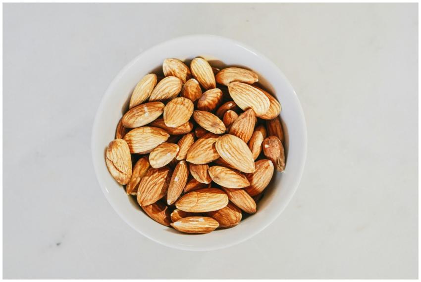 A close-up of raw almonds in a white bowl, highlig