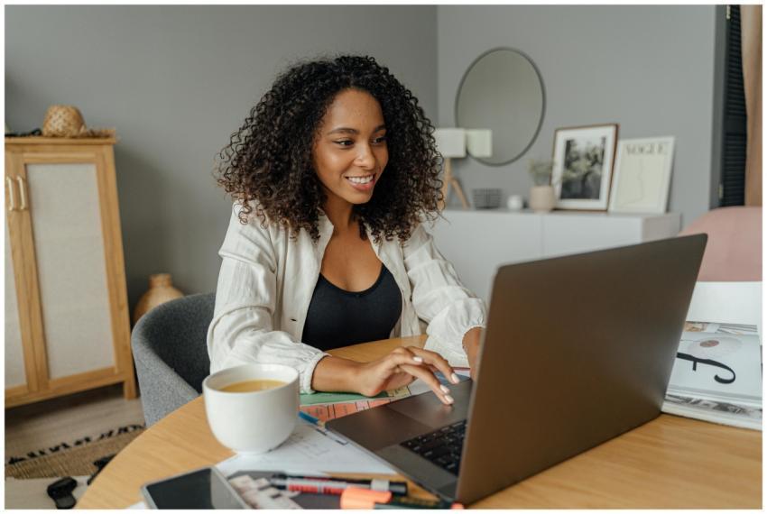 A woman sits at a round table, working on a laptop