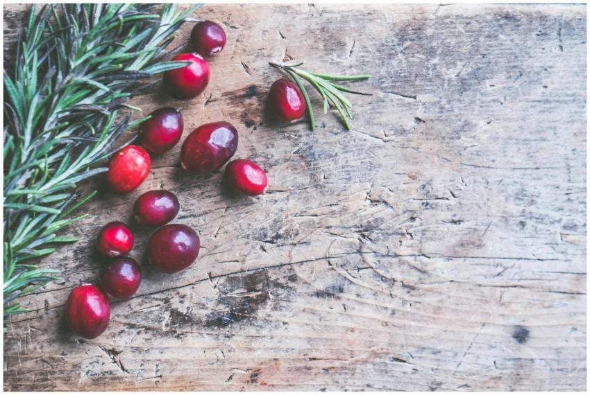 Top view of cranberries and rosemary on a rustic w
