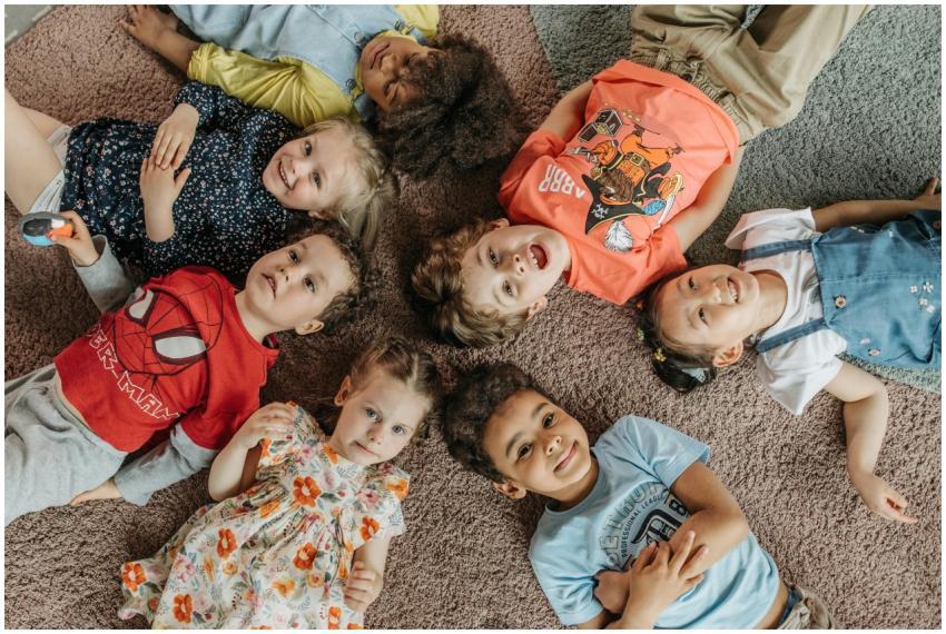 A joyful group of children lying on carpet, formin