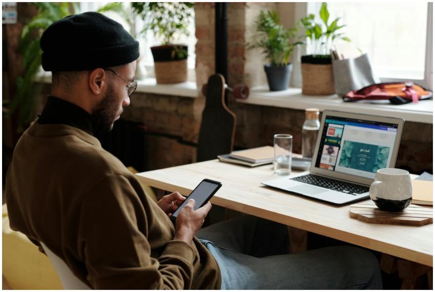 Male designer working on laptop and phone in a mod