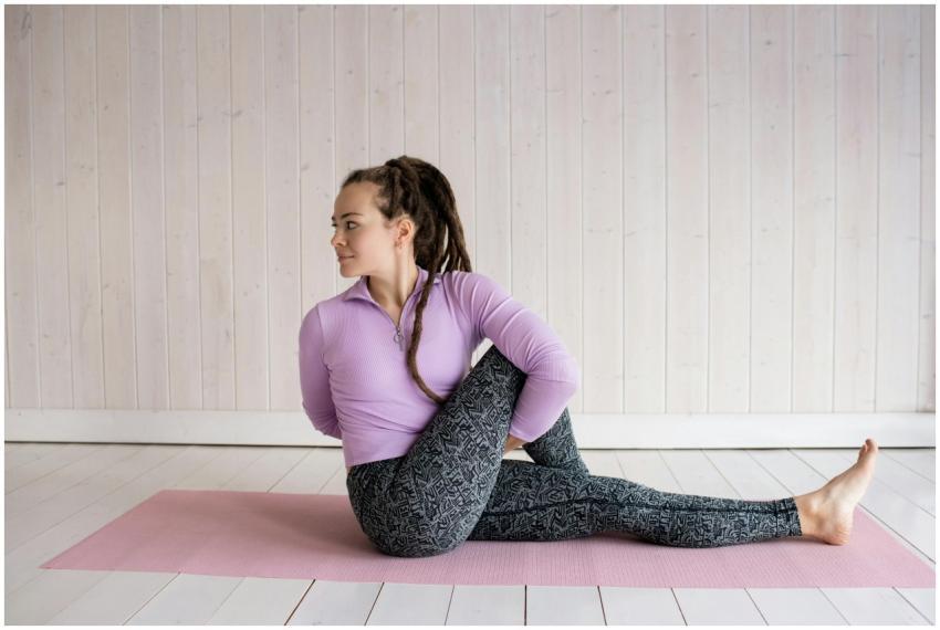 A woman performs a seated twist yoga pose on a pin