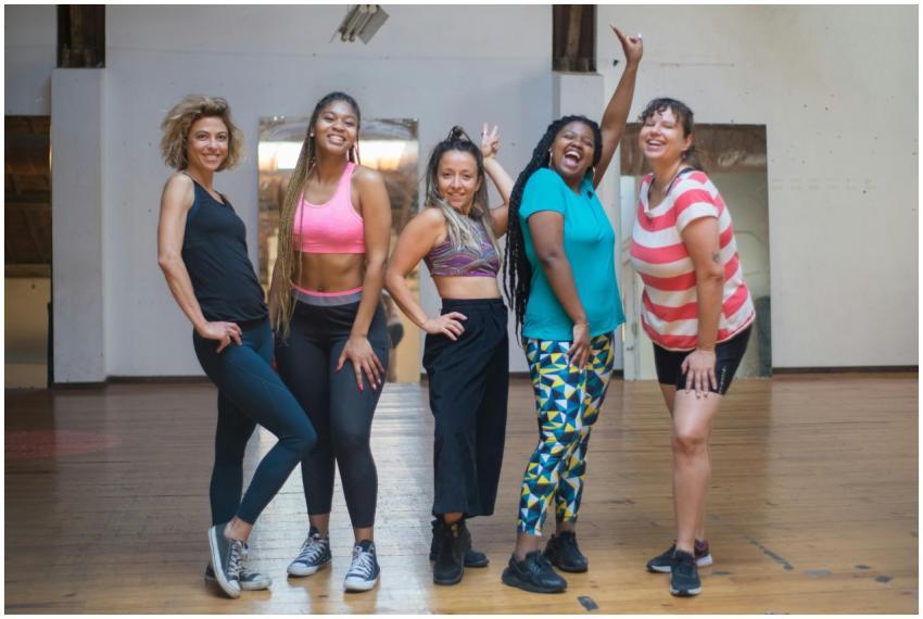Five diverse women joyfully pose in a dance studio