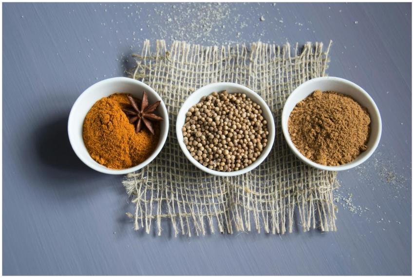 Flat lay of aromatic spices in bowls on a textured