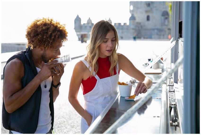 Woman eating fried potato with sauce standing near