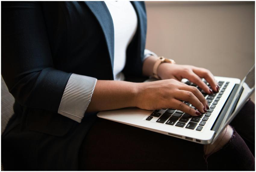 Woman in a blazer typing on a laptop in a well-lit
