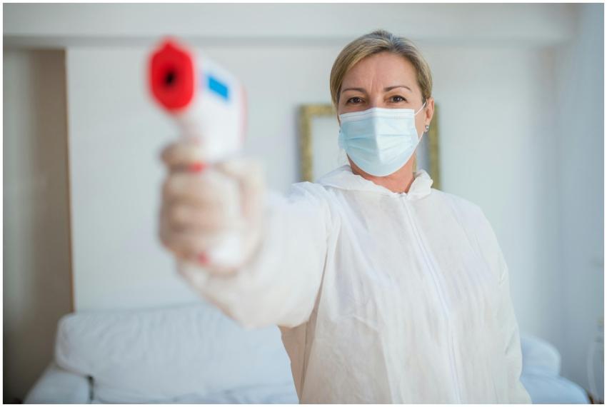 Masked healthcare worker in PPE using infrared the