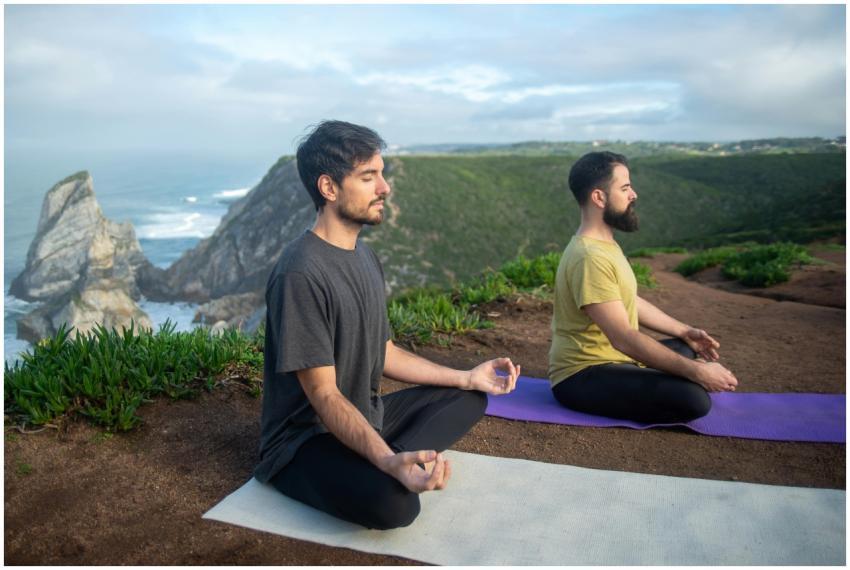 Two men practicing meditation on yoga mats overloo