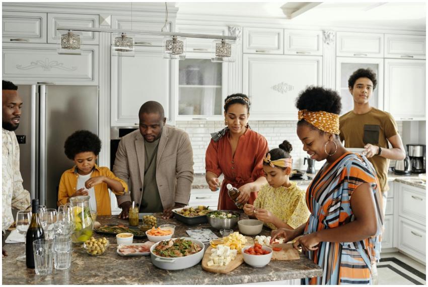 A happy family gathers in the kitchen to prepare a