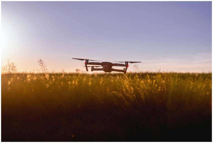 A drone flies over a field during sunset, capturin