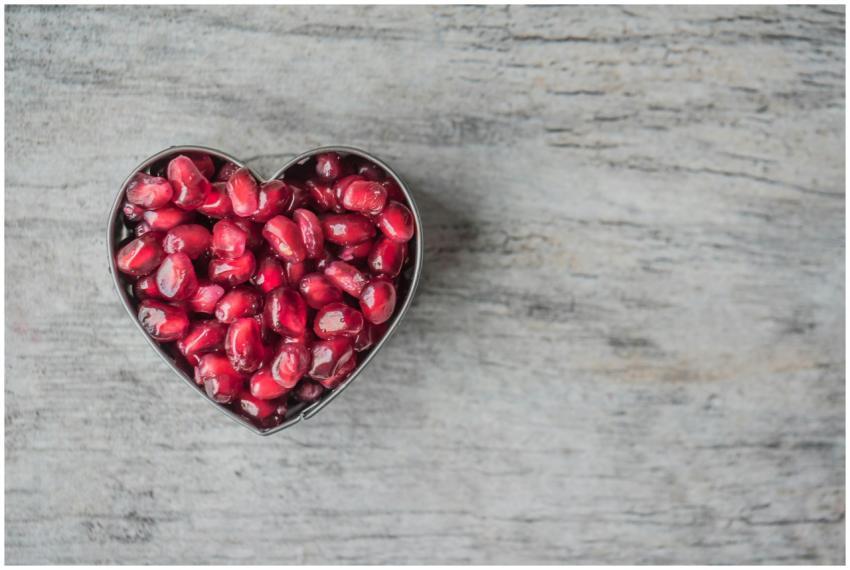 Delicious and juicy pomegranate seeds in a heart-s