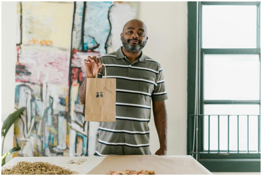 A smiling entrepreneur holding a paper bag with st