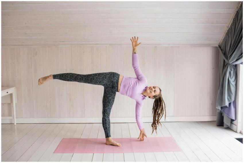 Woman practicing yoga pose indoors on a pink mat,