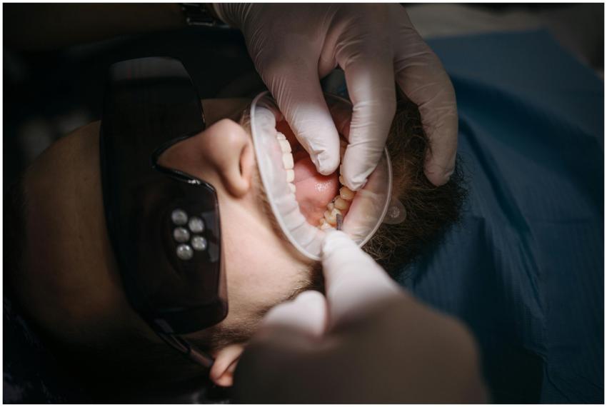 A dentist's hands examining a patient's teeth usin