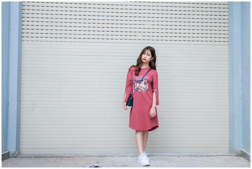 Stylish young woman in a casual dress leaning agai