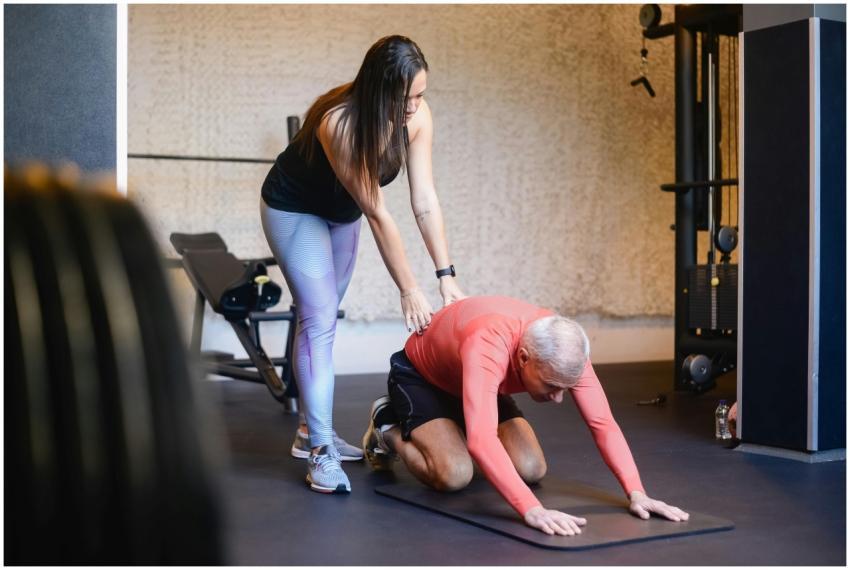 Elderly man assisted by trainer during a workout s