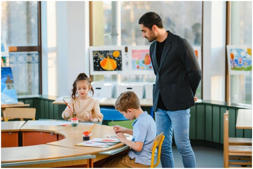Young students painting in a classroom with teache