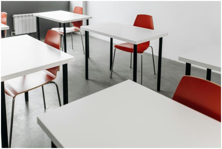 Minimalist classroom setup with red chairs and whi
