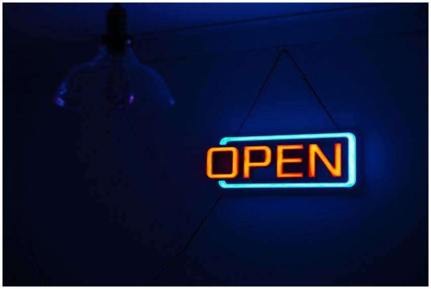 Brightly lit 'Open' neon sign against a dark backg