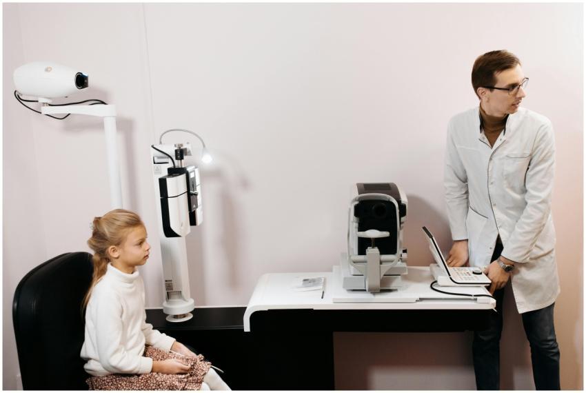 A young girl sits for an eye exam with an optometr