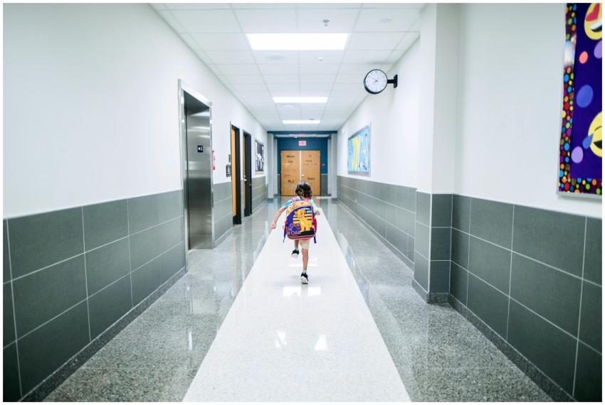 A child runs through a bright school hallway, emph