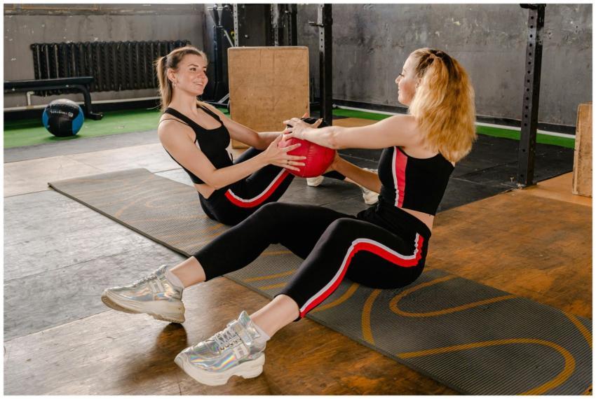 Two women exercising with a medicine ball in a gym