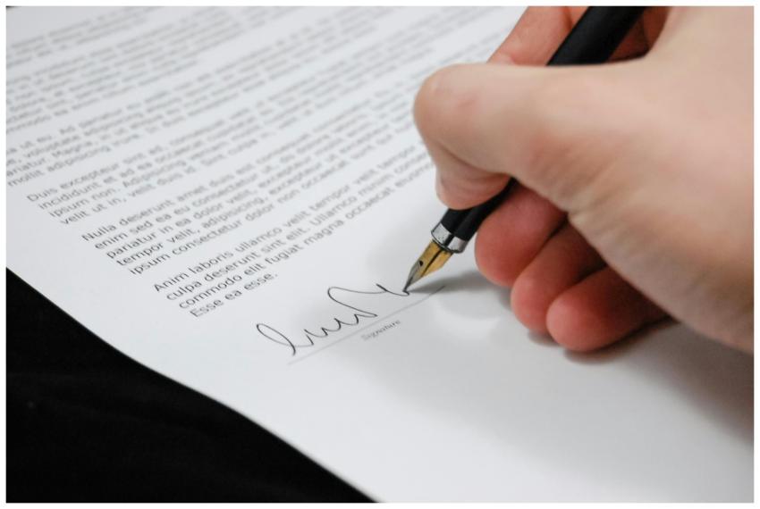 Close-up of a hand signing a legal document with a