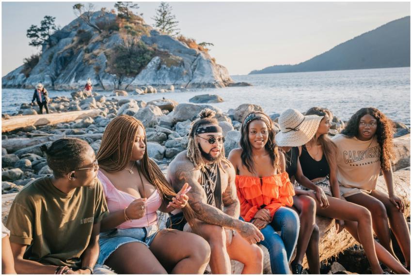 A group of friends relax together on a rocky beach