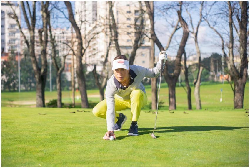 Woman golfer in yellow pants focusing before makin